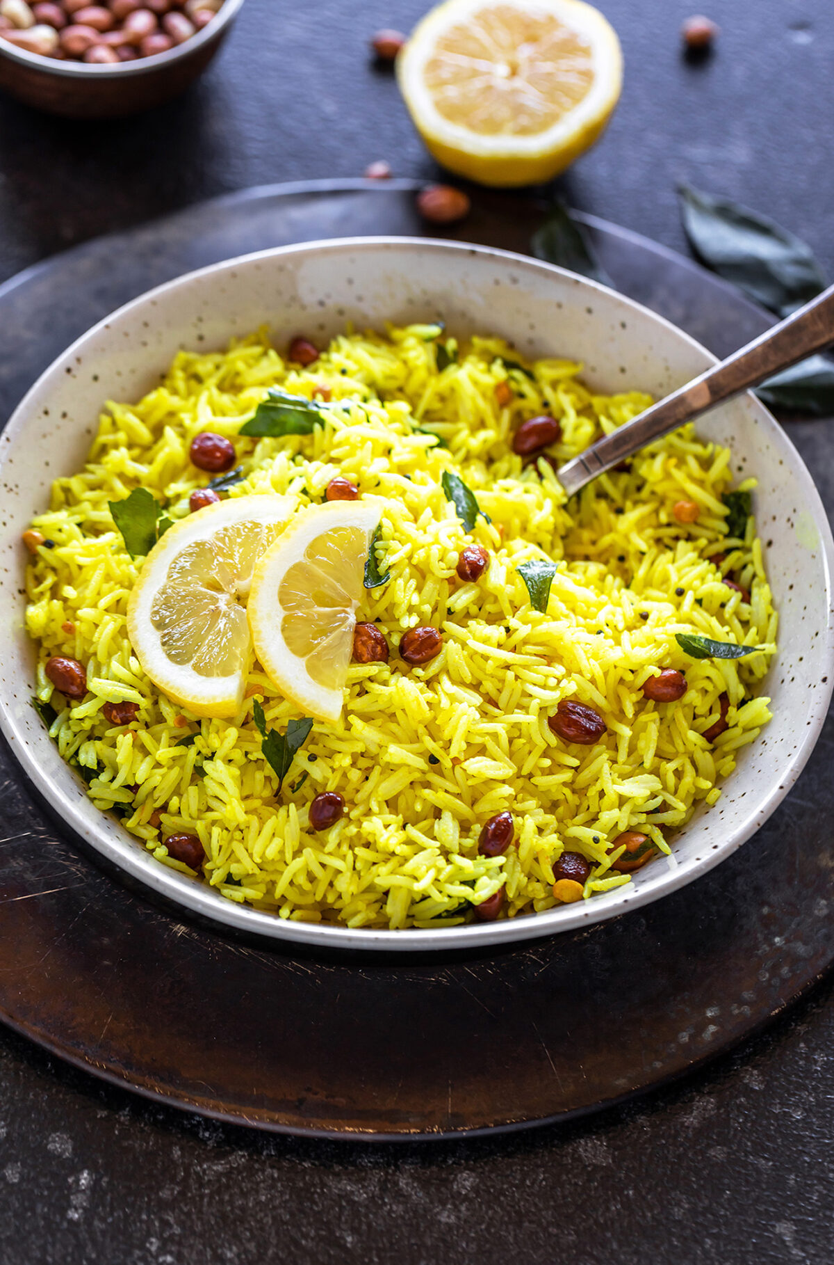 lemon rice served in a white bowl with two lemon sliced place on top