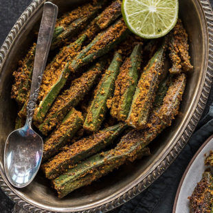 piccante bharwa bhindi in un ovale piatto di ottone, servito con un contorno di lime