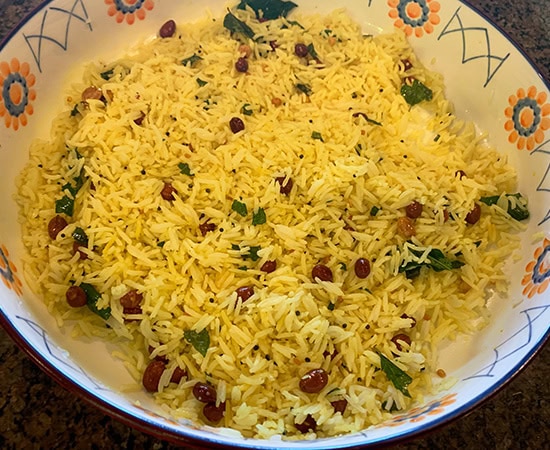 yellow color rice in a bowl topped with peanuts