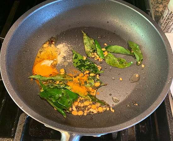 turmeric, curry leaves added to a pan