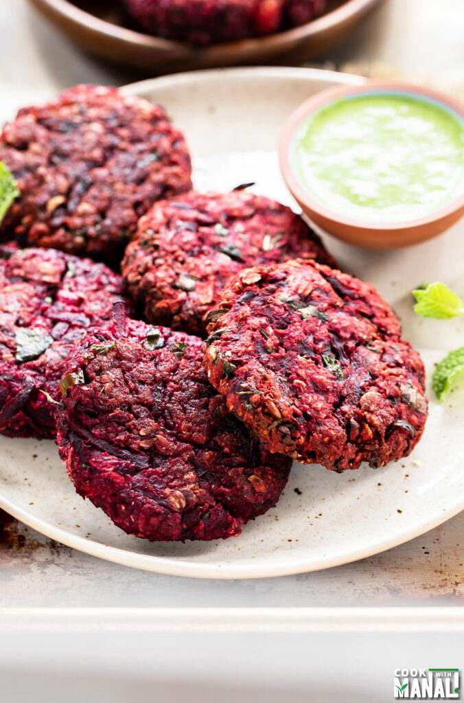 beetroot tikkis arranged on a plate with bowl of chutney on the side