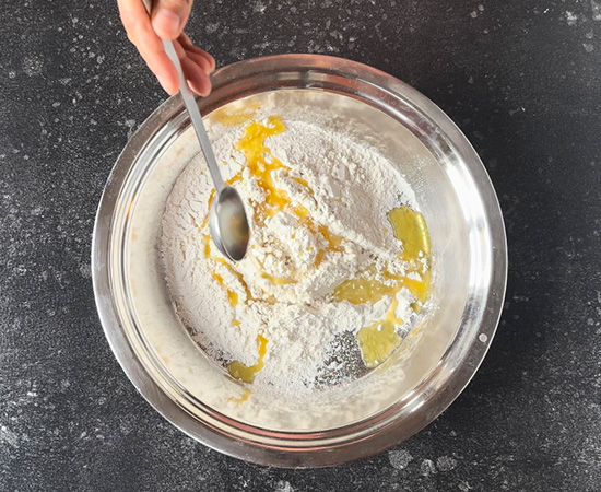 flour in a wide bowl and ghee being added to it