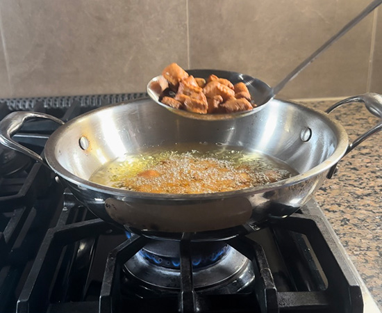 fried shakarpara being take out from hot oil using a strainer
