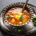 vrat wale aloo served in an antique bowl with a spoon on the side