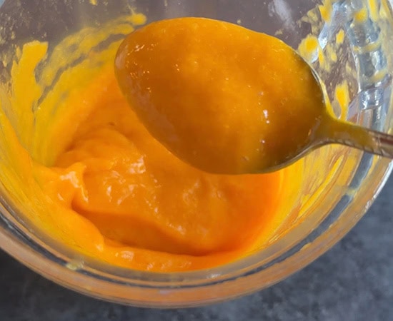 a spoon showing the texture of fresh mango puree