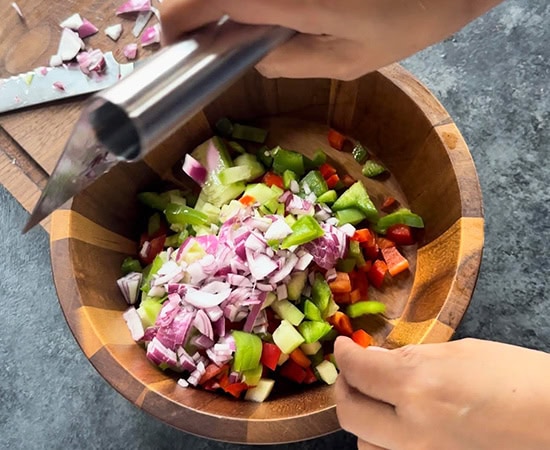 adding chopped veggies to a bowl using a bench scraper