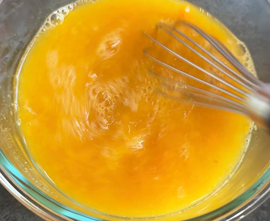 a wire whisk stirring mango puree with water