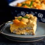 slice of mango tiramisu served in a blue plate with a fork placed on the side