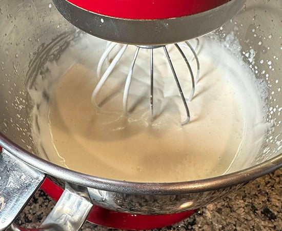 heavy cream being whisked by wire whisk in a stand mixer