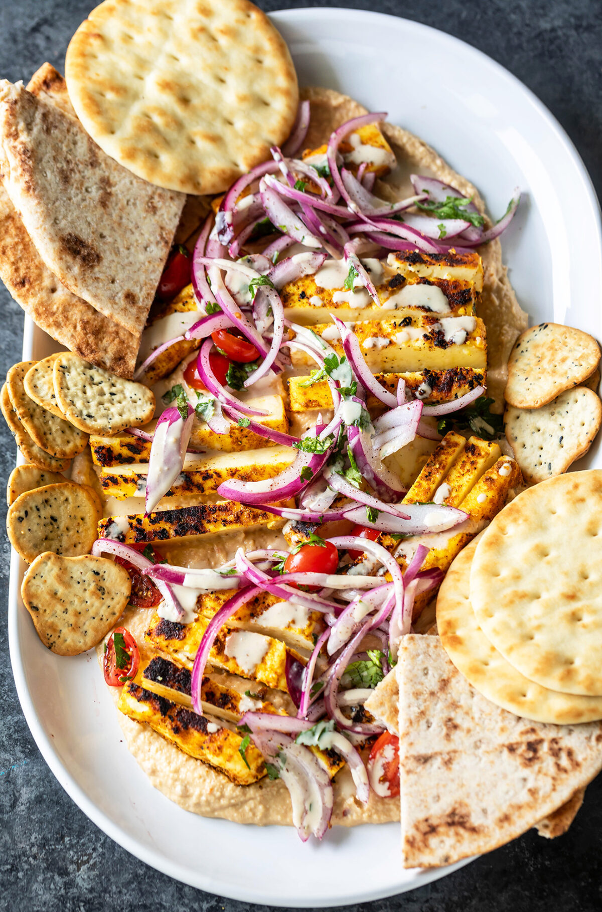 paneer with hummus arranged on a platter with naans placed on the side