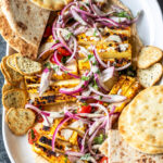 paneer with hummus arranged on a platter with naans placed on the side