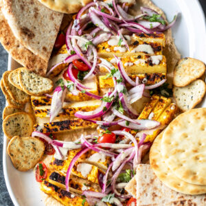 paneer with hummus arranged on a platter with naans placed on the side