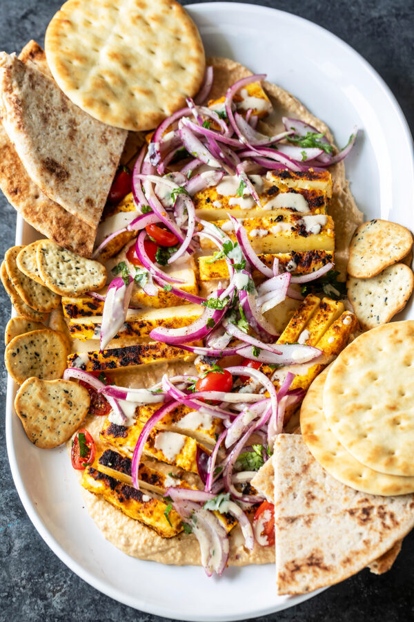 paneer with hummus arranged on a platter with naans placed on the side