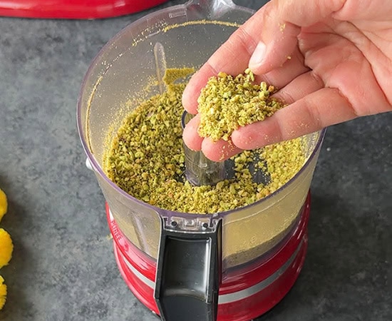 hand showing crushed pistachios in a food processor