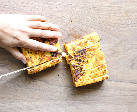 knife cutting paneer slabs into strips