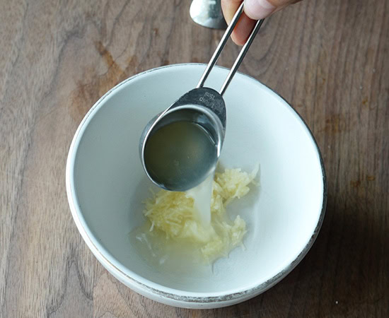 a spoon adding lemon juice to minced garlic