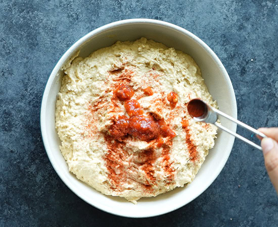 adding chilli powder to hummus