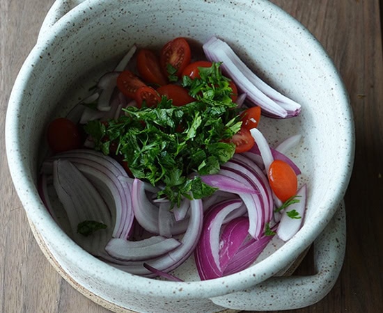 sliced onions, chopped tomato and parsley in a bowl