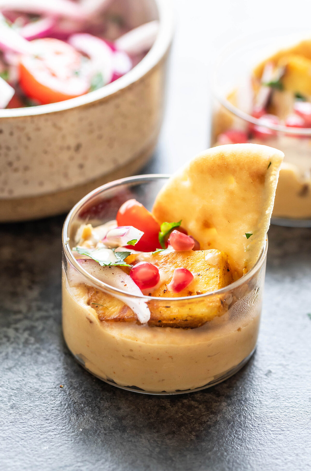 hummus with paneer served in a small glass bowl with naan placed on the side