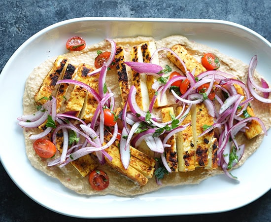 hummus topped with paneer, sliced onions, tomatoes