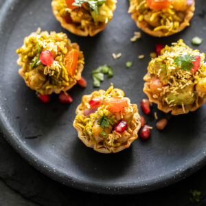 5 phyllo shells filled with chickpea, avocado arranged in a round black plate