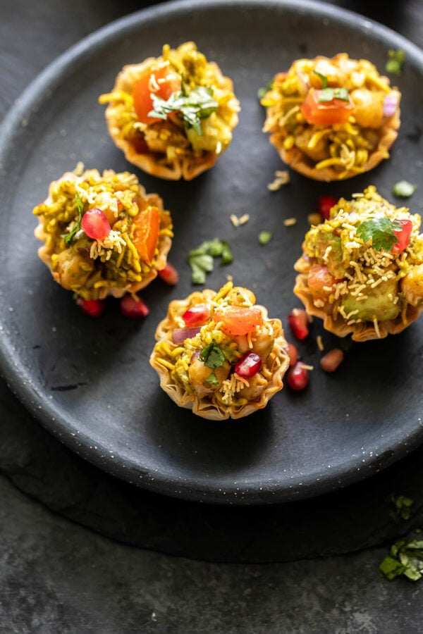 5 phyllo shells filled with chickpea, avocado arranged in a round black plate