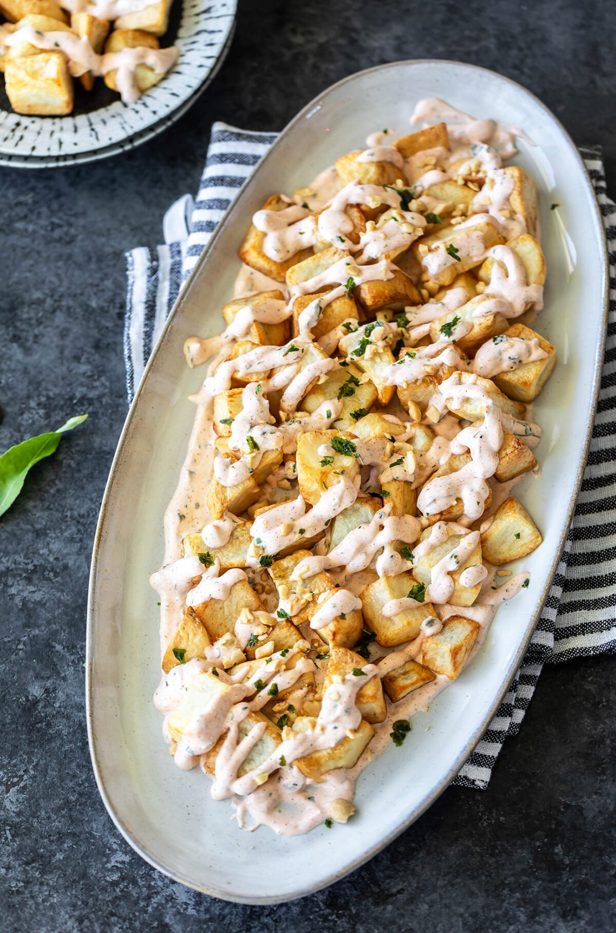 cubed fried potatoes on a serving plate topped with a sauce