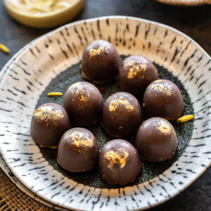 9 chocolate truffles dusted with edible gold arranged in a plate