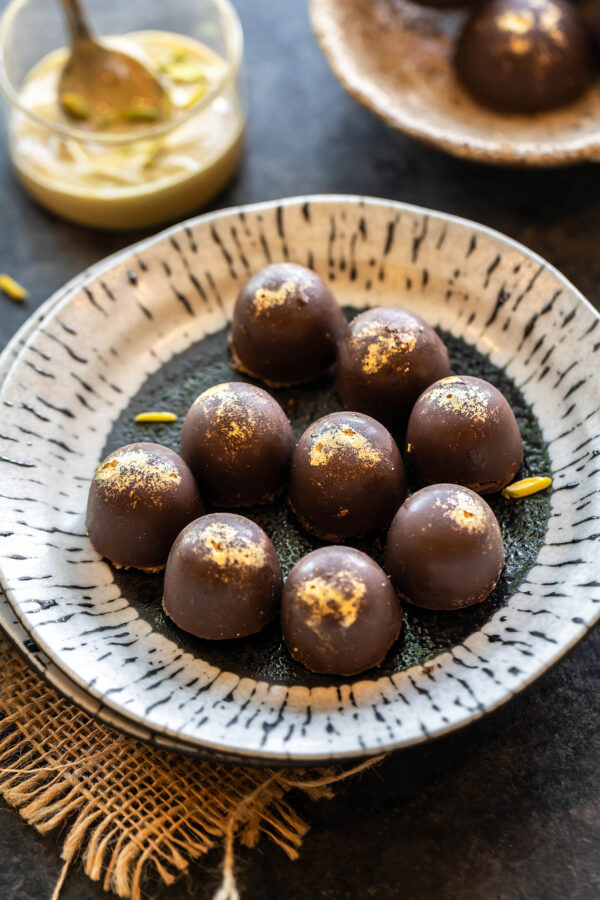 9 chocolate truffles dusted with edible gold arranged in a plate