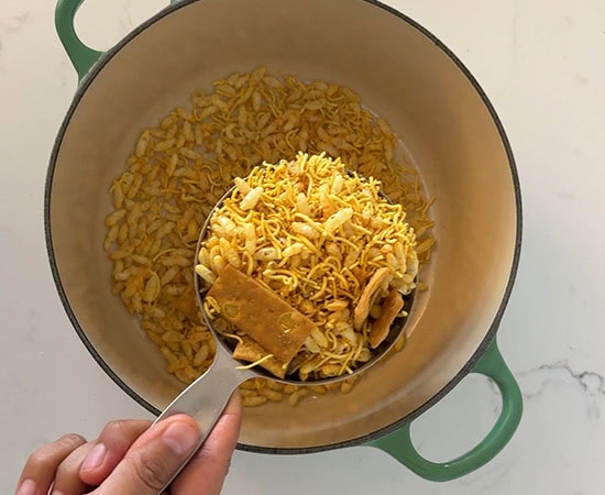 1 cup full of bhel mix being added to a pot