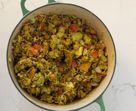 a pot with bhel mix with chickpea, avocado, tomatoes