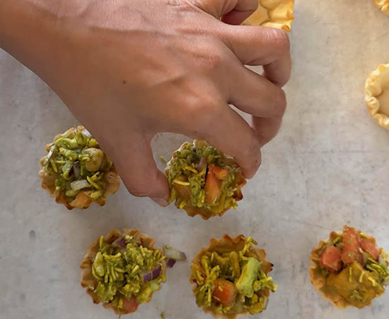 a hand holding a phyllo shells with more shells lying around