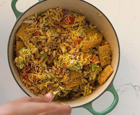 a hand mixing the content of a pot using a spoon