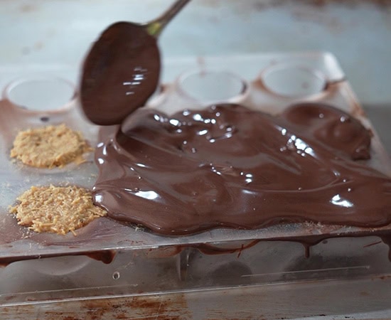 a spoon putting melted chocolate over truffles