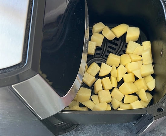 cubed potatoes air arranged in an air fryer