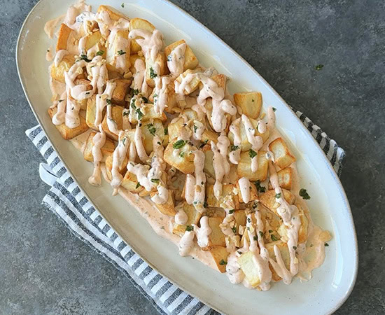 a plate with cubed fried potatoes topped with sour cream sauce