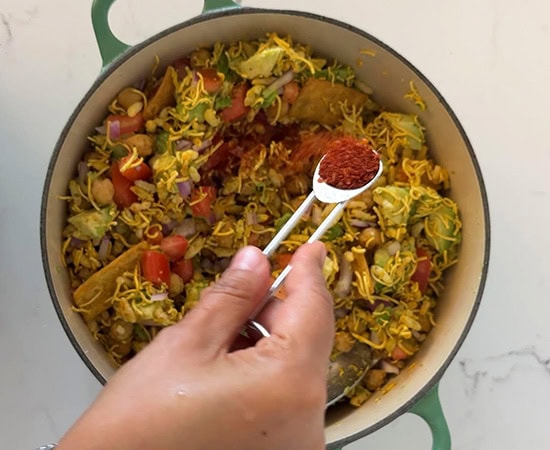 red color dry chutney being added to a pot