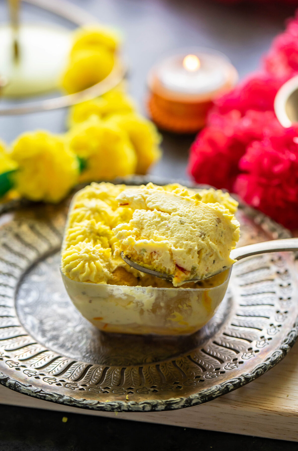 a spoon digging into bowl of kesar pista tiramisu to show it's texture