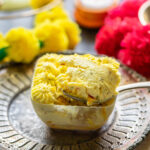 a spoon digging into bowl of kesar pista tiramisu to show it's texture