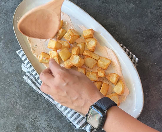 hand arranging fried potatoes in a platter