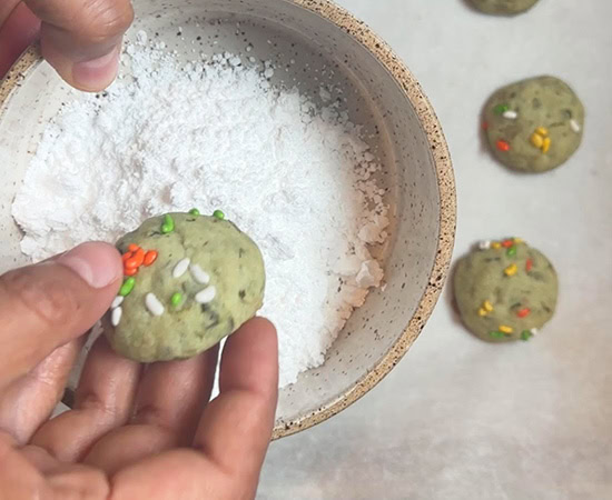 paan cookies being transferred to a bowl of powdered sugar