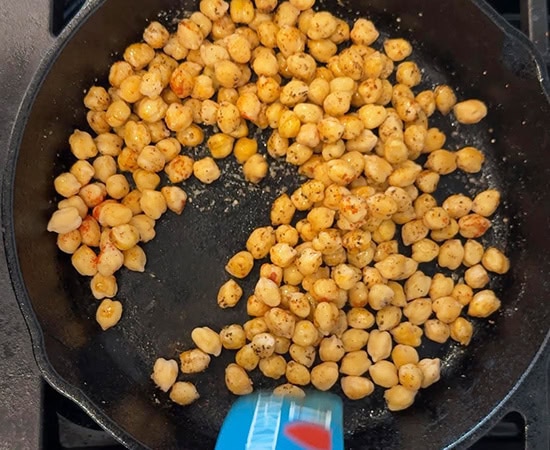 a spatula stirring chickpeas in a pan