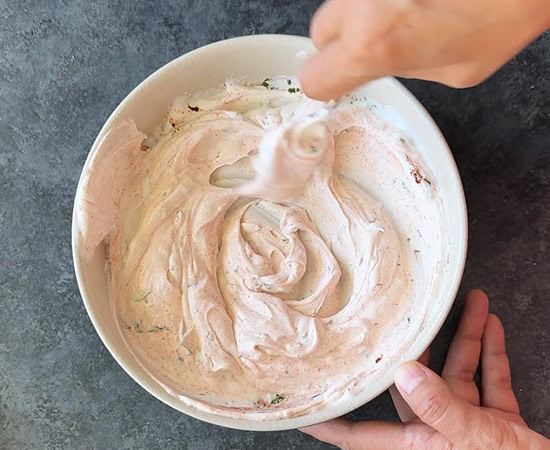 hand whisking dip in a bowl