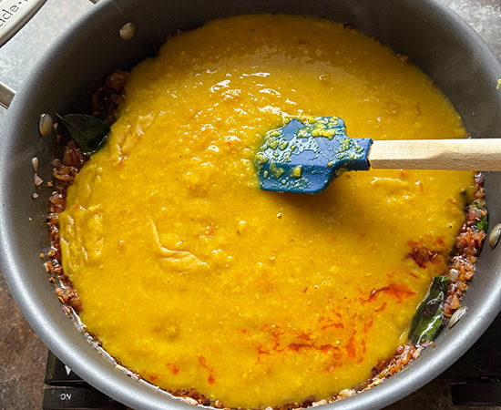 cooked masoor dal added to the tadka in a pan